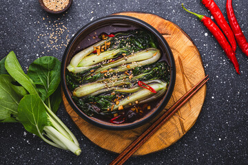 fried pak choi cabbage with garlic and soy sauce, Pak Choi or Bok Choy on dark grey background, top view