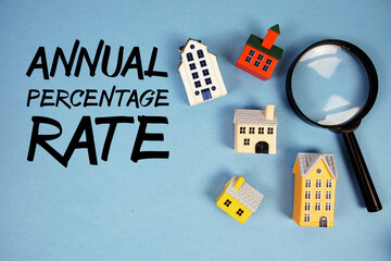 APR Annual Percentage Rate text with house models and magnifying glass on blue background