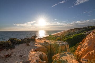 Scenic sunset over cliffs, pine forest, and golden beach in Mazagon, Huelva, Spain. Tranquil seascape ideal for travel, nature, and landscape concepts.