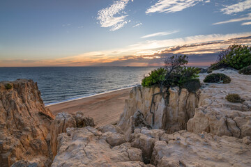 Scenic sunset over cliffs, pine forest, and golden beach in Mazagon, Huelva, Spain. Tranquil seascape ideal for travel, nature, and landscape concepts.