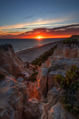 Scenic sunset over cliffs, pine forest, and golden beach in Mazagon, Huelva, Spain. Tranquil seascape ideal for travel, nature, and landscape concepts.