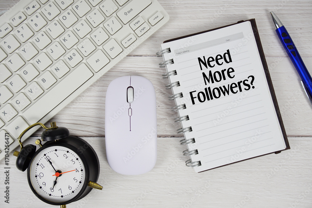 Poster need more followers? text with alarm clock, keyboard and wireless mouse on wooden background