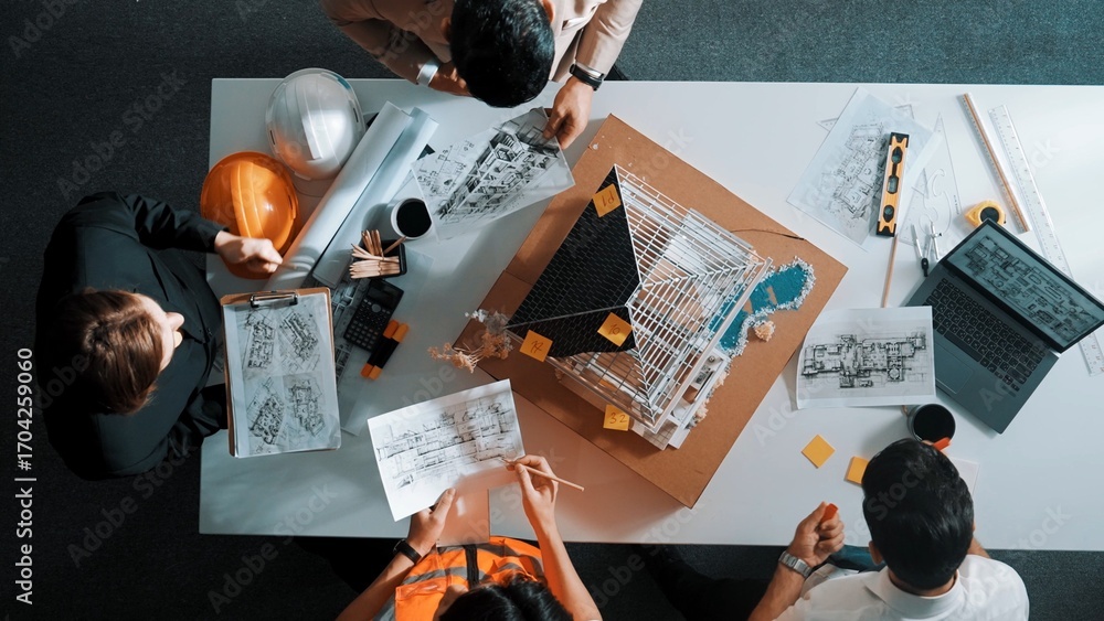 Poster top view of manager handed blueprint to professional engineer team at meeting table with house model
