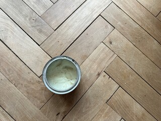 Wood wax for parquet care — a jar on a wooden floor. Concept of interior care, eco-friendly protection, and durability.