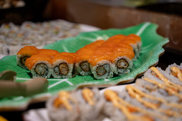 Close up of salmon sushi rolls with fried shrimp filling on green plate.