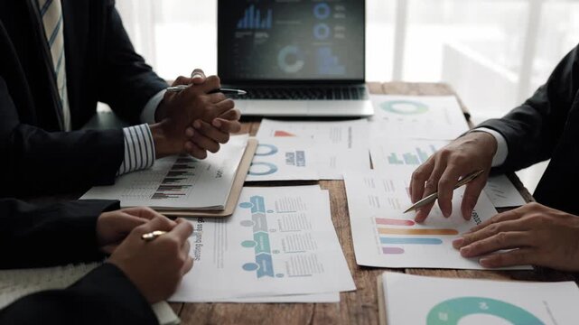 Financial team carefully analyzing performance charts and graphs, sharing strategic insights during collaborative corporate meeting