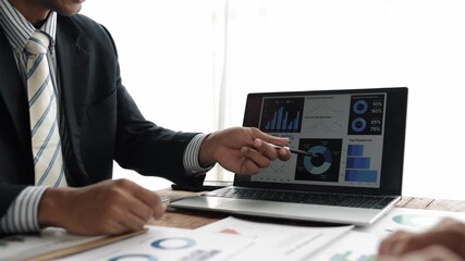 Professional reviewing financial charts on laptop, revealing team's strategic data analysis during corporate collaboration meeting - Powered by Adobe