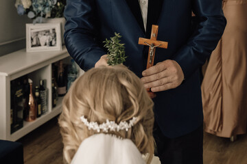 Wedding blessing tradition bride receiving cross and greenery ritual before church ceremony symbolic moment of faith family and love on wedding day in Christian celebration