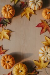 Fototapeta premium A wooden table with a pumpkin and a few leaves. The pumpkin is orange and the leaves are yellow