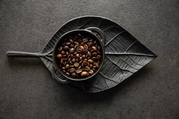 Ziarna kawy w miseczce na tle ozdobnej tacy w kształcie liścia Coffee beans in a bowl on a decorative leaf-shaped tray
