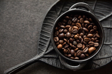 Ziarna kawy w miseczce na tle ozdobnej tacy w kształcie liścia Coffee beans in a bowl on a decorative leaf-shaped tray