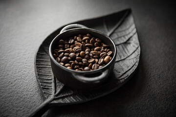 Ziarna kawy w miseczce na tle ozdobnej tacy w kształcie liścia Coffee beans in a bowl on a decorative leaf-shaped tray