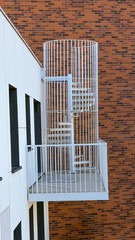 A white staircase with a fence to access the terrace against a brick wall