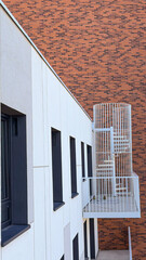 A white staircase with a fence to access the terrace against a brick wall