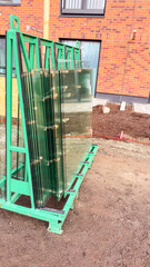 A lot of cut glass for balconies stacked on a special holder at the construction site