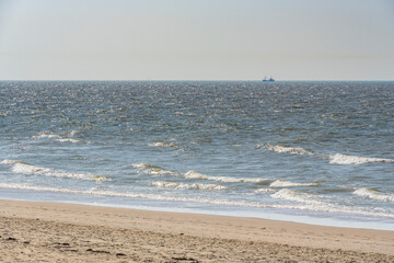 single ship is sailing on the North Sea, ship, sails and waves shine in the evening light, North Sea beach before sunset with waves of the ocean