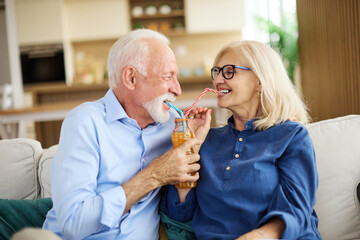 Portrait of a lovely senior  couple having fun and laughing sharing a drink together at home