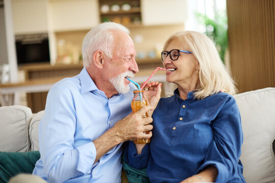 Portrait of a lovely senior  couple having fun and laughing sharing a drink together at home - Powered by Adobe