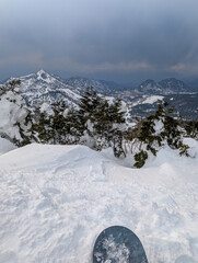 Obraz premium Snowboarder's perspective looking over snow covered trees and mountains in Japan.