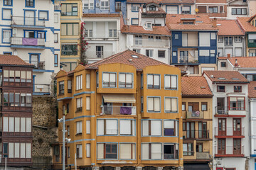 Fototapeta premium Colorful Basque Coastal Buildings With Traditional Bay Windows And Terracotta Roofs In Historic Fishing Village. Northern Architecture Wooden Shutters
