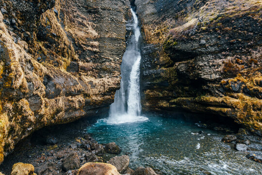 Gljufrabui waterfall cascading 40 meters through narrow rocky canyon in South Iceland's Hamragardar gorge. Hidden behind mossy cliff formations