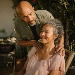 Man giving a massage to a woman outdoors in a garden during sunny day