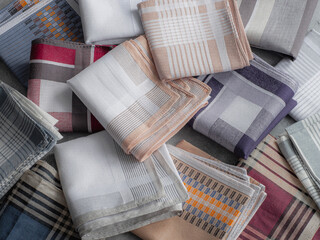 A diverse collection of neatly folded men's handkerchiefs with a variety of classic patterns and colors is shown in a close-up, top-down view.