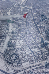 Snow-covered cityscape viewed from an airplane wing during a winter flight over urban landscape