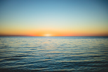 Vibrant sunset over tranquil ocean waters creates peaceful evening atmosphere