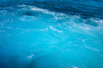 Vibrant turquoise waves gently rolling in under bright sunlight at a coastal location