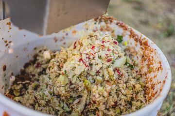 Cooking preparation of a fresh coleslaw mix with colorful vegetables at an outdoor event