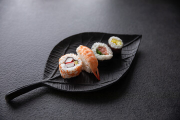 Zestaw sushi na czarnej tacy w kształcie liścia Assorted sushi on a black leaf-shaped tray