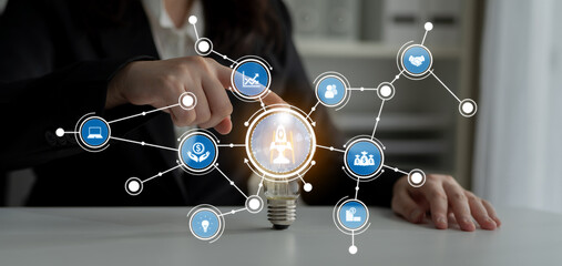 A focused businesswoman activates an innovative concept represented by a glowing light bulb, emphasizing collaboration, technology, and creative solutions in the workplace. Crux