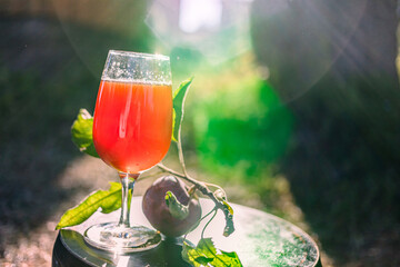 Refreshing apple juice served in a glass with a sunny backdrop and vibrant greenery during a warm afternoon