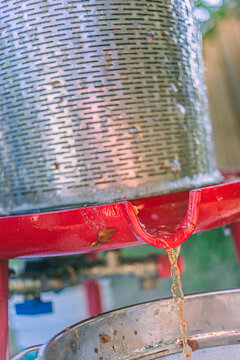 Apple Juice draining from a metal hydropress strainer into a bowl during a food preparation process