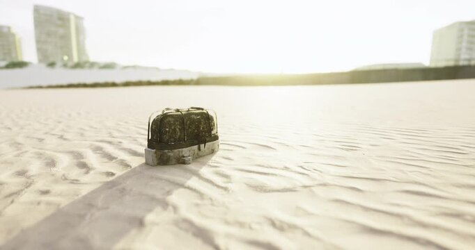 A lonely bag rests on the golden sands, silhouetted against the glowing sun. The gentle breeze stirs the grains, creating patterns as day transitions into night, evoking curiosity.