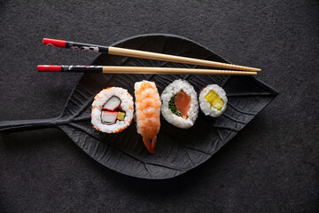 Zestaw sushi na czarnej tacy w kształcie liścia Assorted sushi on a black leaf-shaped tray