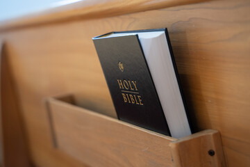 Holy Bible placed in wooden church pews.
