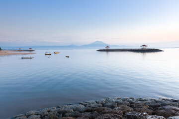 Scenic panorama of Sanur beach at sunrise with a volcano on the background, Bali, Indonesia