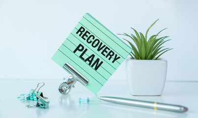 A green clipboard with the word recovery plan written on it