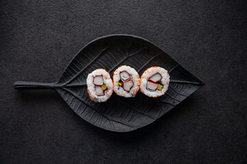 Zestaw sushi na czarnej tacy w kształcie liścia Assorted sushi on a black leaf-shaped tray