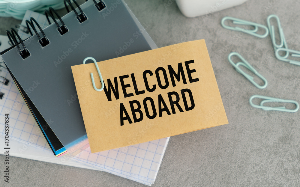 Poster on the table are paper clips, note paper with text - welcome aboard