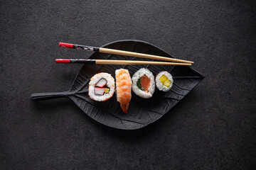 Zestaw sushi na czarnej tacy w kształcie liścia Assorted sushi on a black leaf-shaped tray