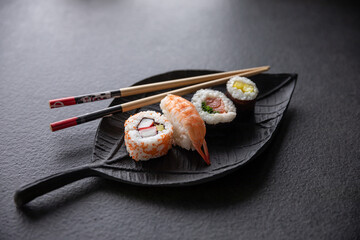 Zestaw sushi na czarnej tacy w kształcie liścia Assorted sushi on a black leaf-shaped tray