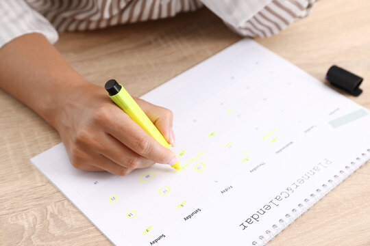 Business planning. Woman with calendar at wooden table in office, closeup