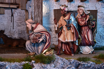 Naklejka premium Weihnachtskrippe im alpenländischen, ländlichen Stil, mit Bergen und Nachthimmel als Hintergrund, in gemütlichem Stall aus alten Holzbalken und stimmungsvoller Beleuchtung