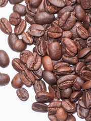 Roasted coffee beans scattered on white background close up