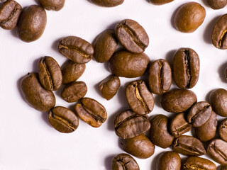 Roasted coffee beans scattered on white background close up
