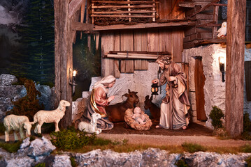Weihnachtskrippe im alpenländischen, ländlichen Stil, mit Bergen und Nachthimmel als Hintergrund, in gemütlichem Stall aus alten Holzbalken und stimmungsvoller Beleuchtung