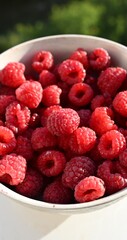 A close-up of a white bowl filled to the brim with vibrant red raspberries, showing off their plump, fresh texture